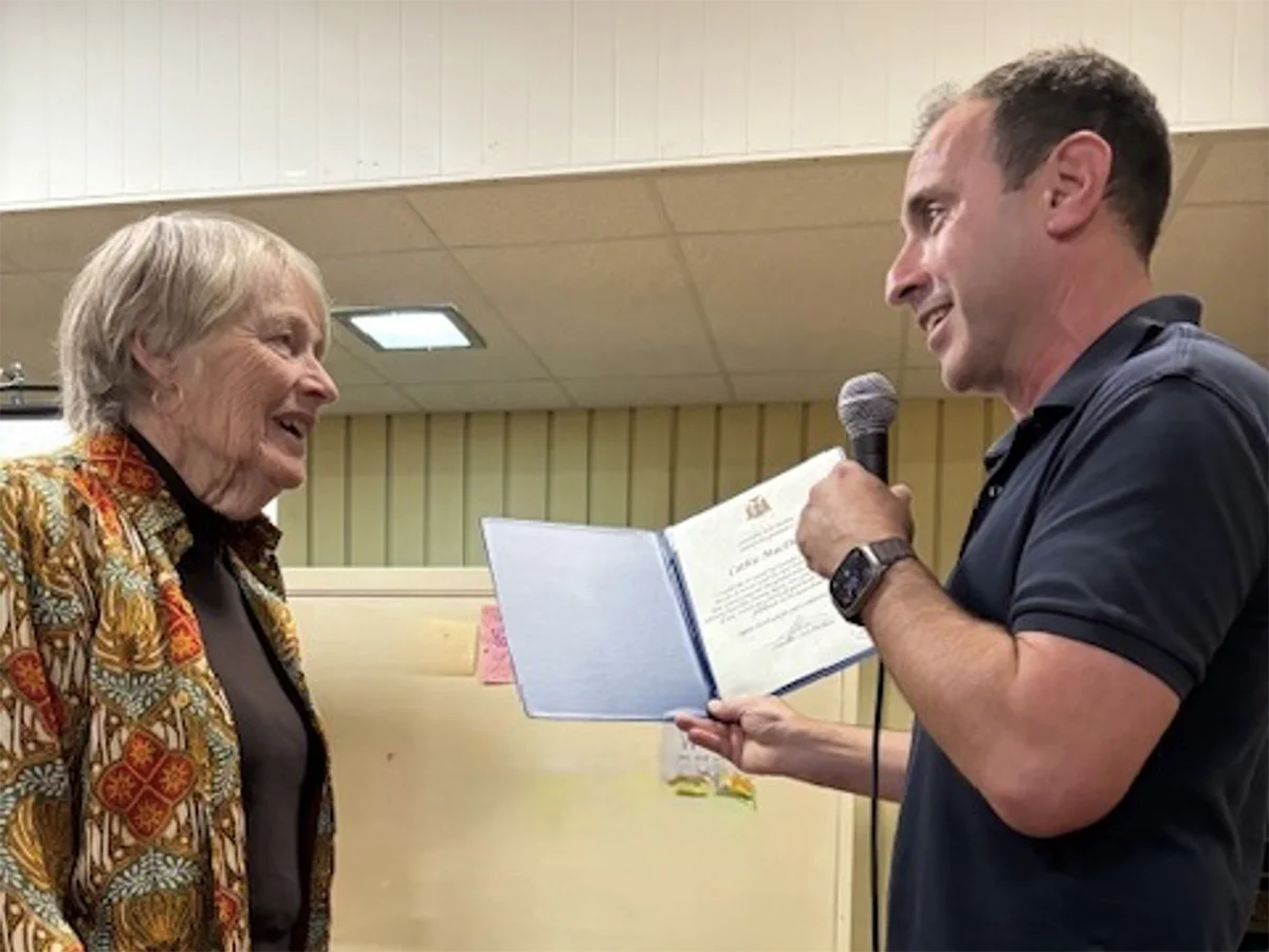 man with microphone presenting a certificate to a woman