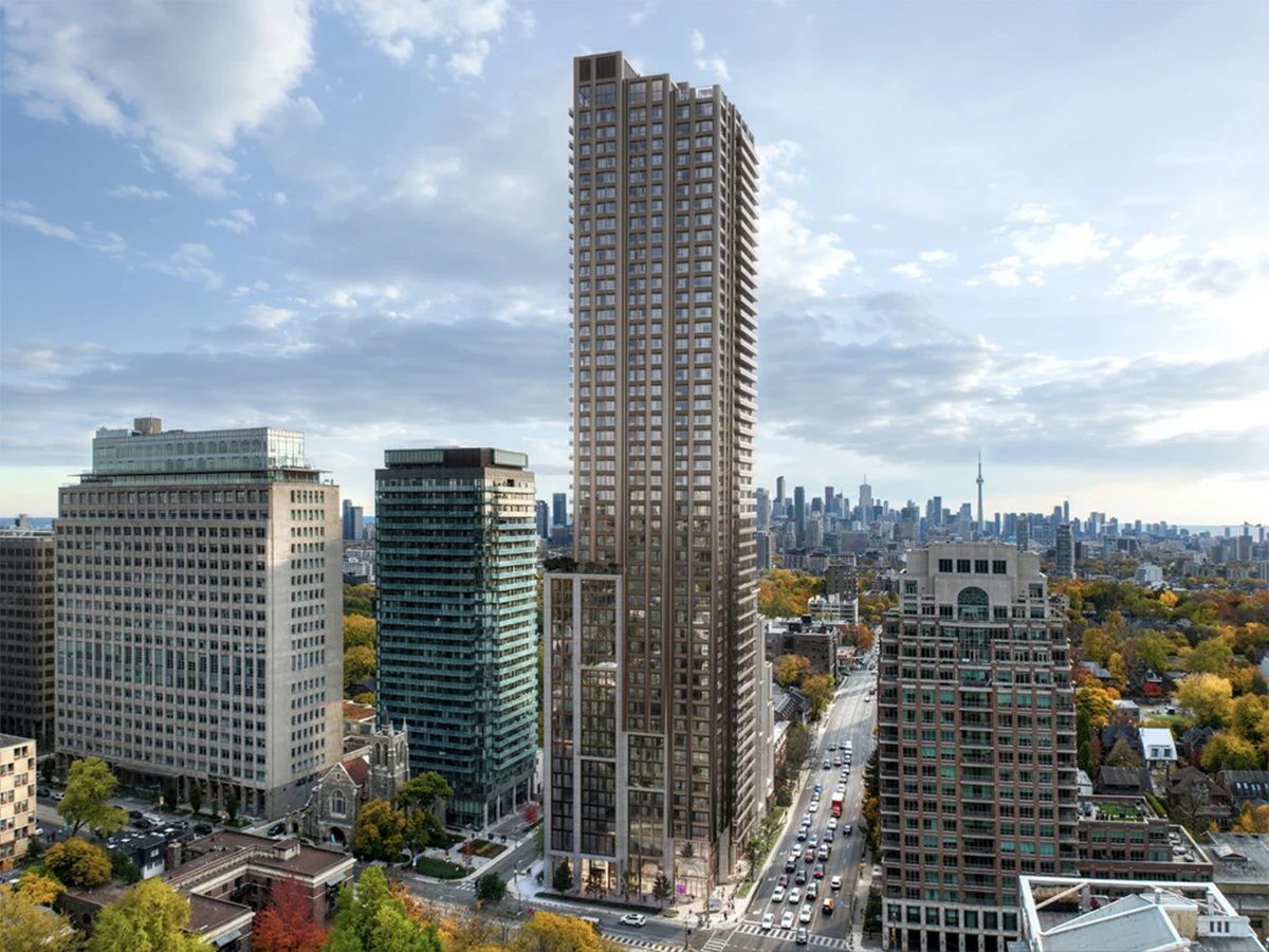 Very tall building surrounded by shorter buildings with city skyline in distance.