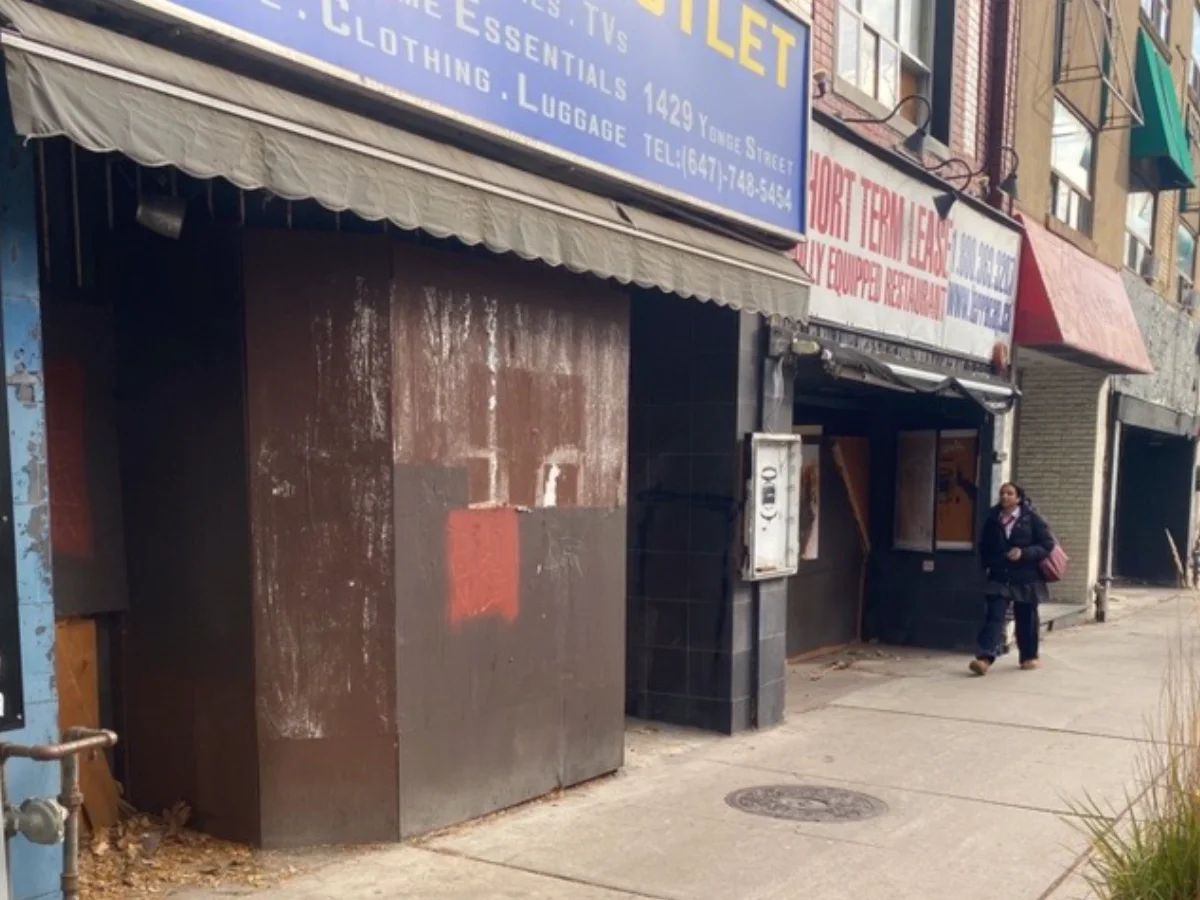 Sidewalk with boarded up former retail stores.